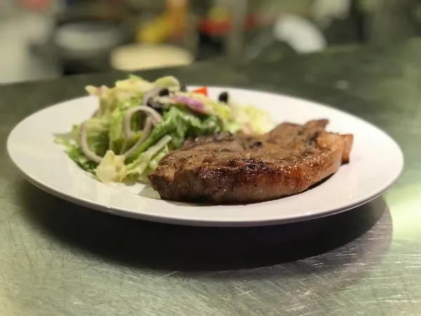 Bistecca ai Ferri, a grilled steak plated with a side salad