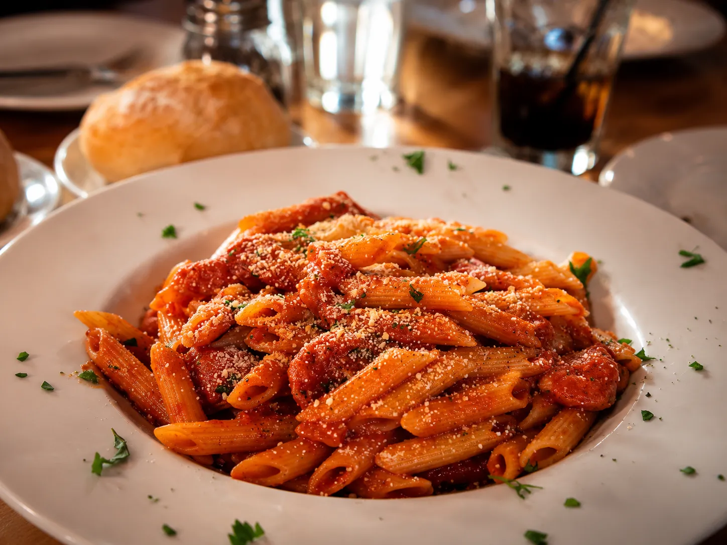 Penne in a hearty meat sauce with grated cheese and a roll