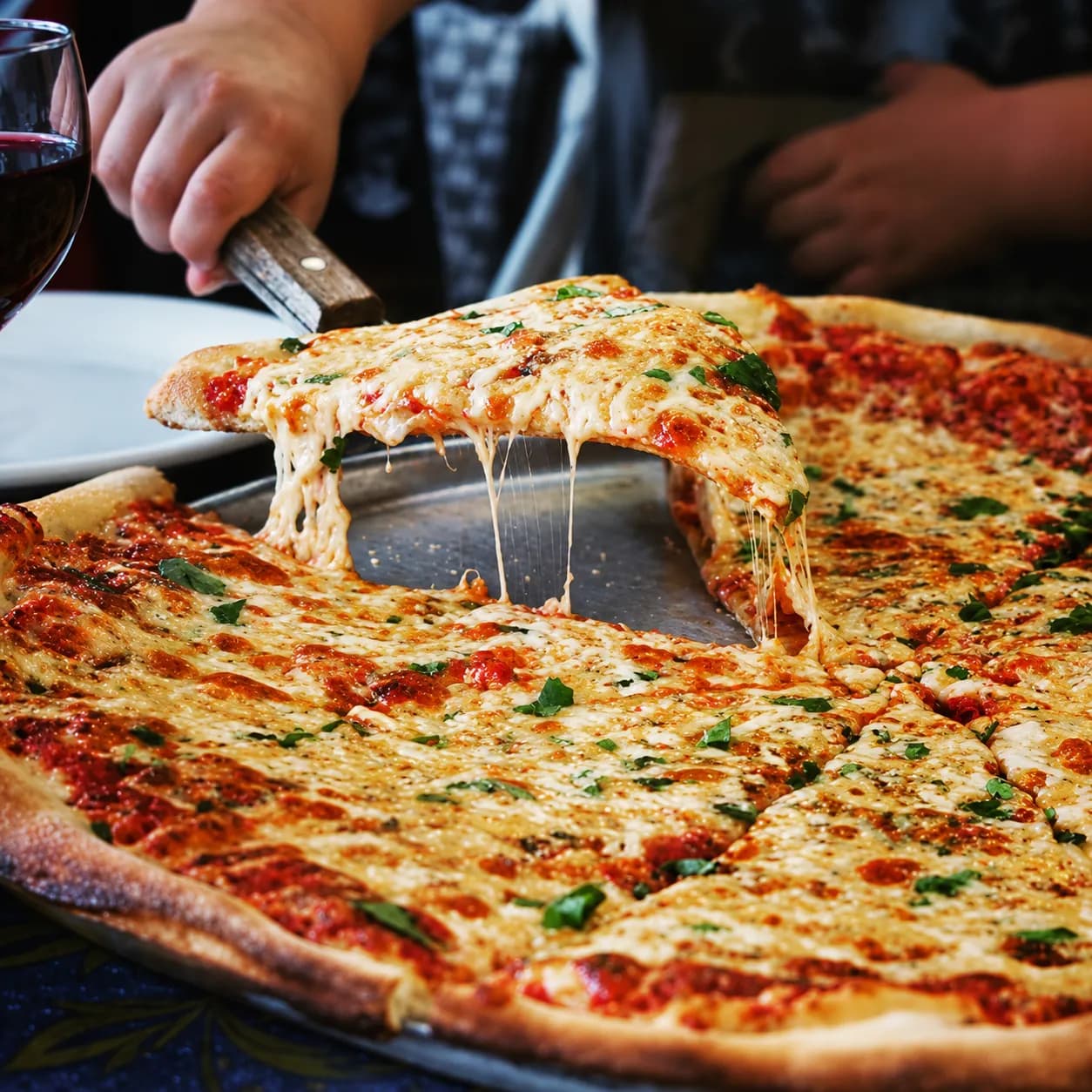 A New York slice lifted from the pie in a long stretch of melted cheese