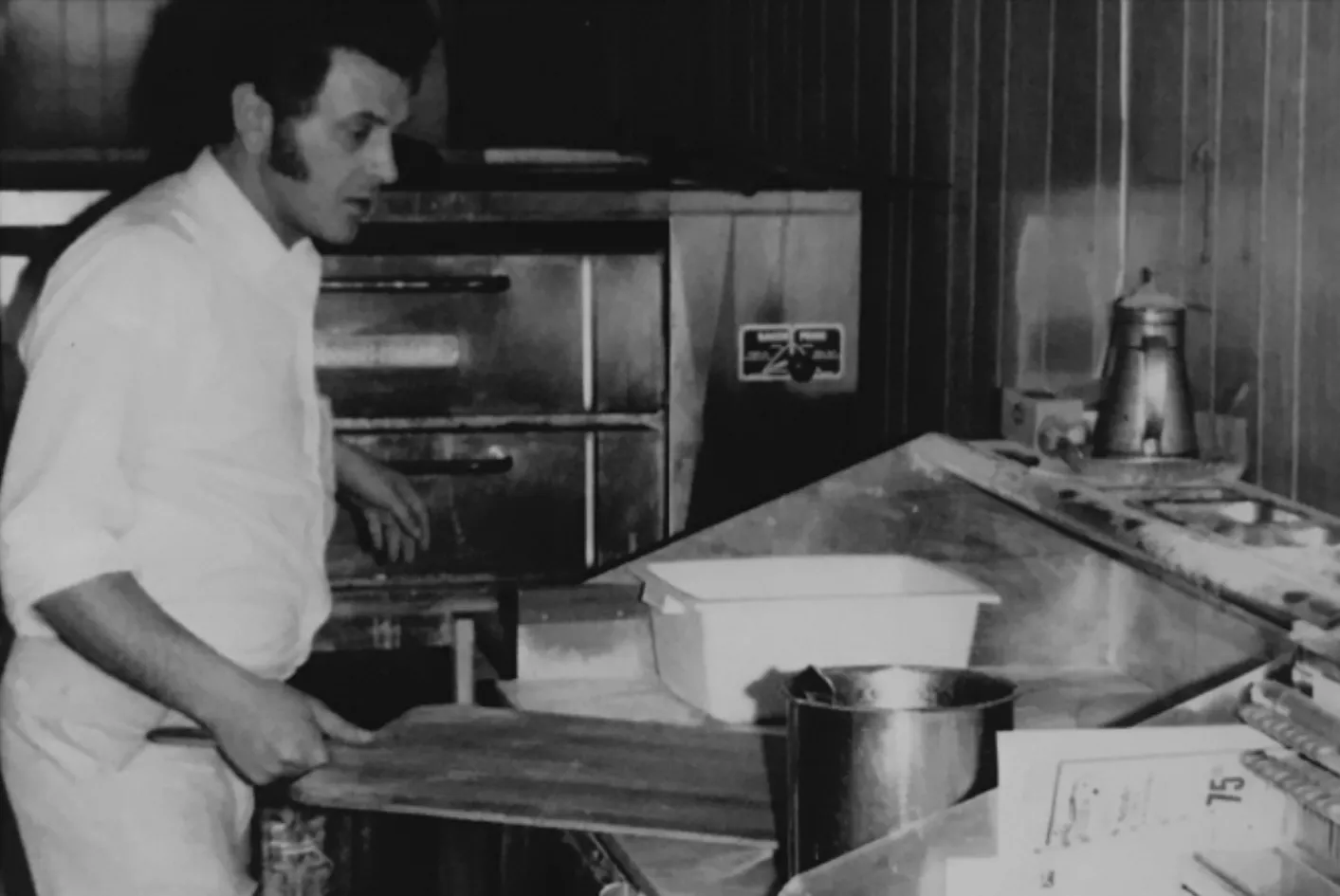 A black and white photograph of dough being worked by hand in the early years